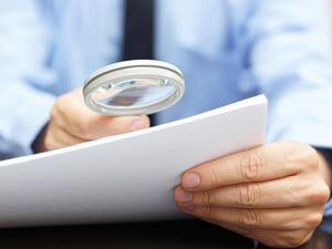 Business man reviewing a document with a magnifying glass