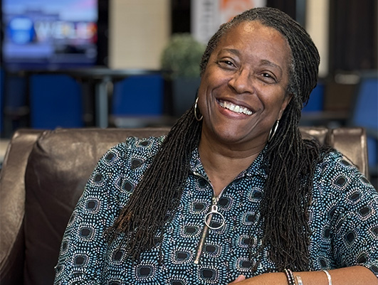 Female business owner of The Well sitting in leather chair smiling at camera.