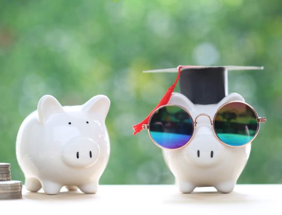 Piggy bank with sunglasses and graduation cap on.