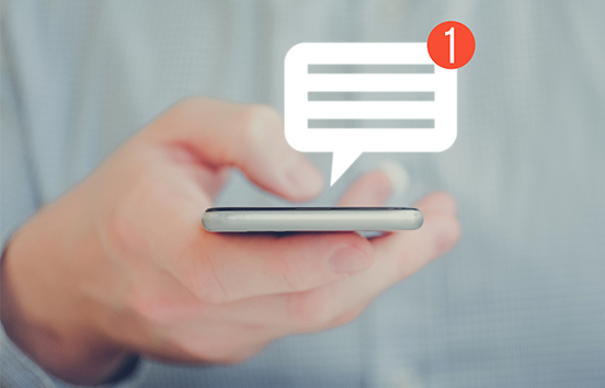 Hand holding mobile phone getting text alerts on account usage 