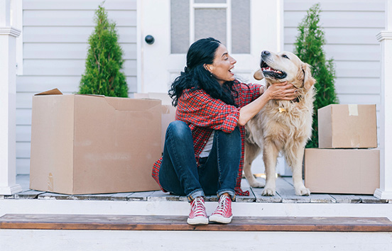 Woman with dog on porch with moving boxes