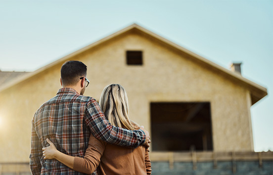 Rear side of couple looking at house under construction 