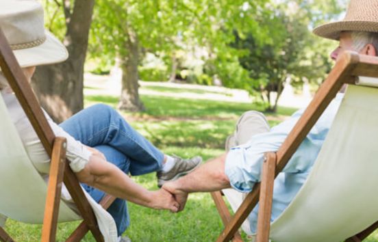 Older couple sitting holding hands outside