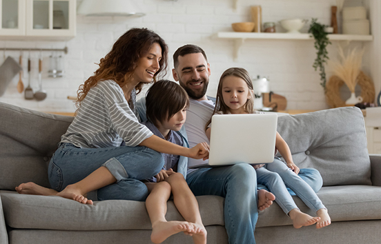 Happy family on couch with computer looking at monitor
