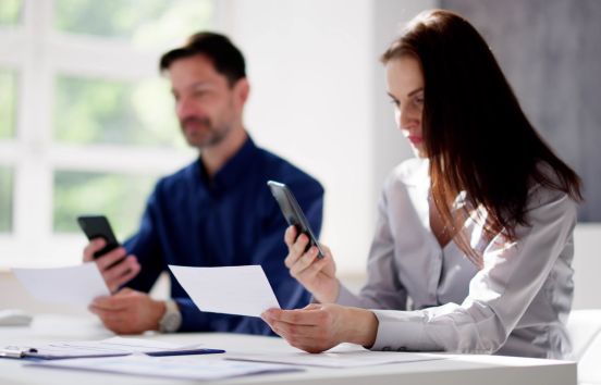 Business couple doing remote deposit at desk