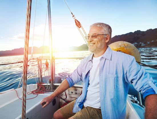 Retired man smiling on small boat on the water.