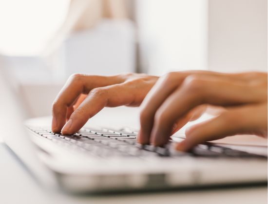 Close up of hands typing on a laptop.
