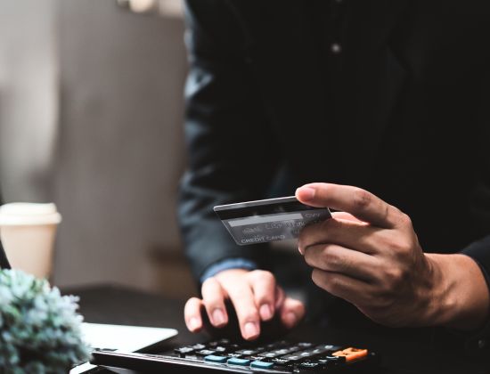 Business owner holding credit card adding on calculator