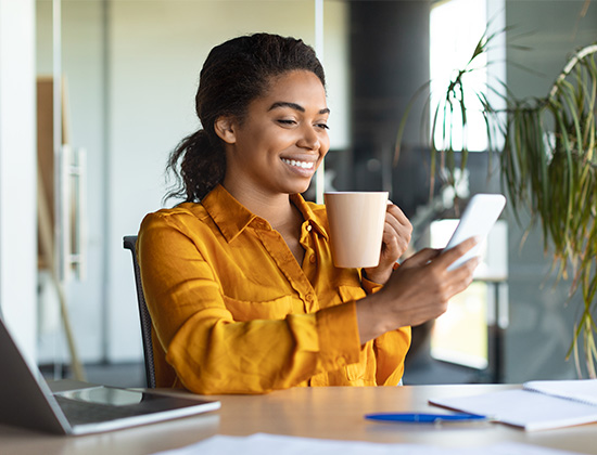 cheerful african american female holding coffee and cellphone