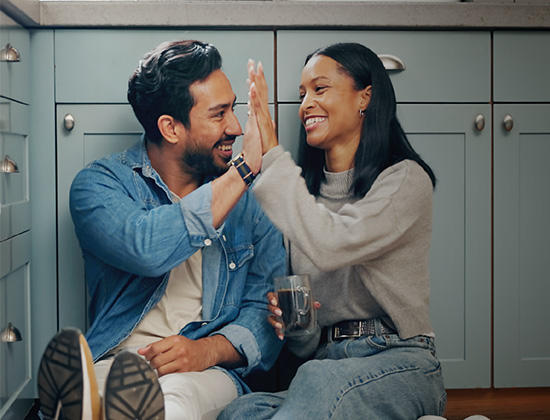 Couple high fiving in the kitchen
