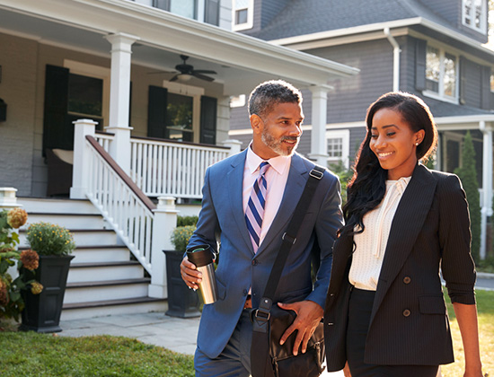 Business Couple Leaving Suburban House For Commute To Work