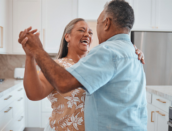 Happy senior couple, dance and laughing in joyful happiness for relationship bonding in the kitchen at home.