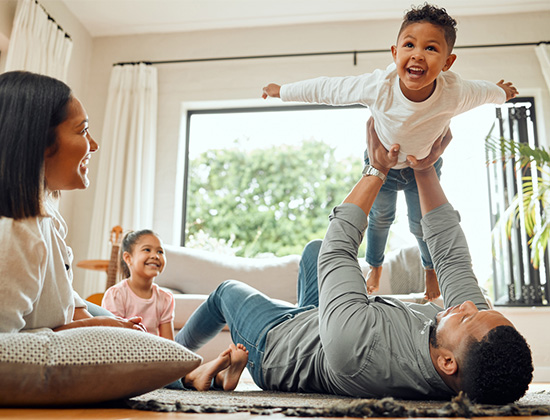 Family of four playing on floor of home