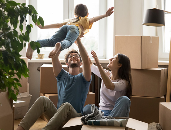 Cheerful young loving family with cute little daughter celebrate moving day, having fun, playing with cute little kid, feel happy at new house, sit on floor near heap of boxes. 
