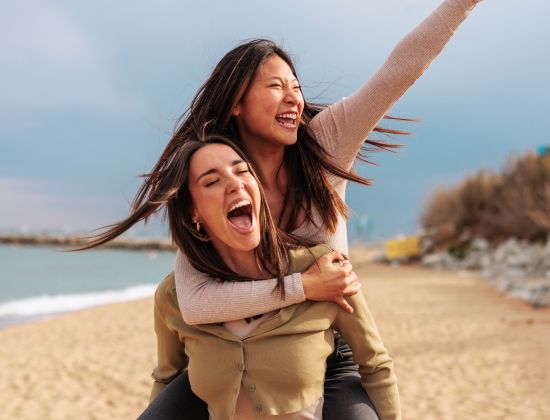 Two young women playing and having fun on beach