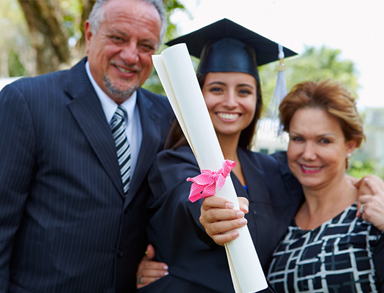 Hispanic Student And Parents Celebrate Graduation Smiling To Camera