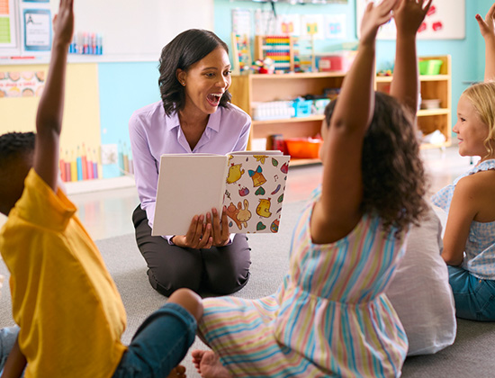 Class Of Elementary School Students Raising Hands To Answer Question In Classroom
