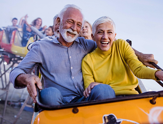 Older couple riding roller coaster at fair