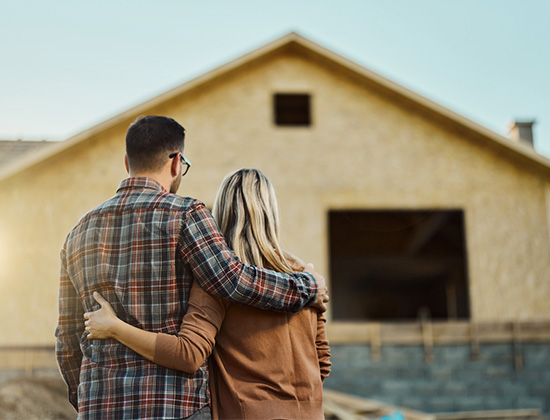 Rear view of an embraced couple looking at built structure from outside.