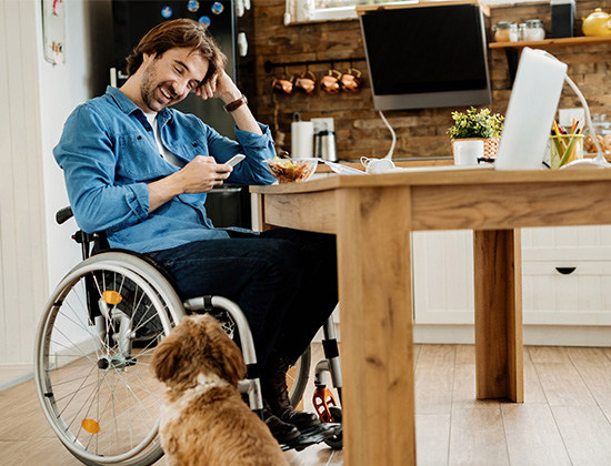 Man in wheelchair at table with dog looking at him