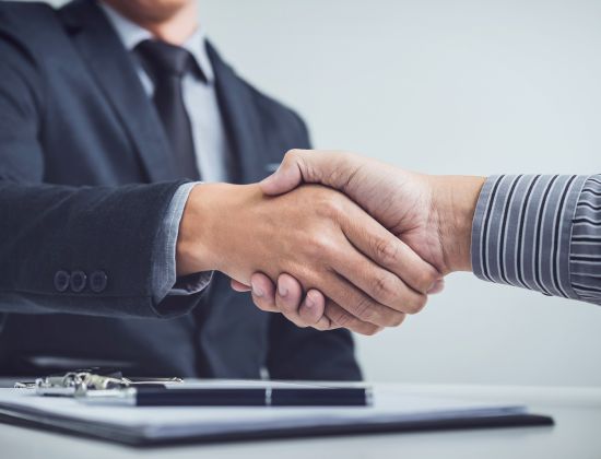 Business professionals shaking hands across desk.
