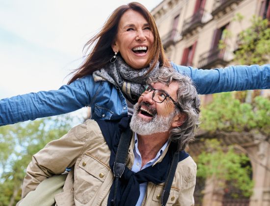 Vacationing middle-aged couple giving piggyback