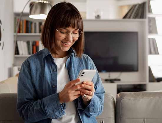 Young woman in living room holding phone