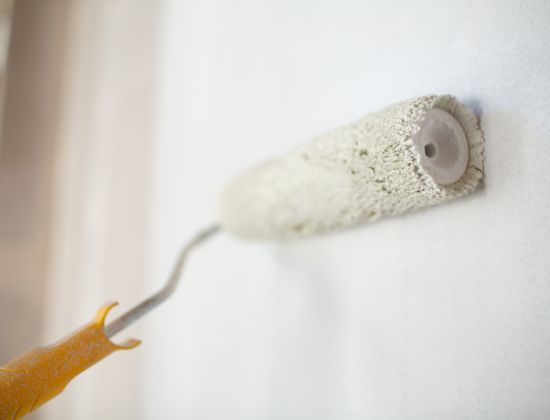 Paint roller on wall with white paint