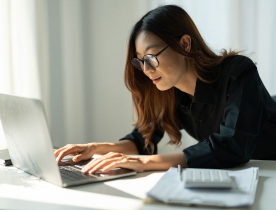 Female business owner looking at laptop to deny ACH transfer