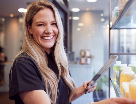 Smiling business owner taking inventory on her iPad.
