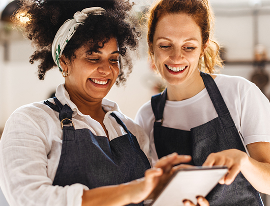 Two women business owners using tablet to check payroll 