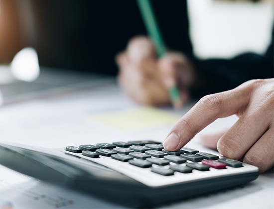 Close up image of a hand using a calculator to add up money to be transferred between accounts
