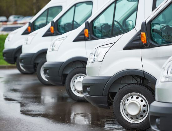 A fleet of white commercial vans parked next to one another.