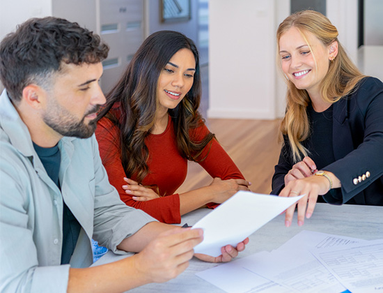 Loan officer with couple looking through documents. 
