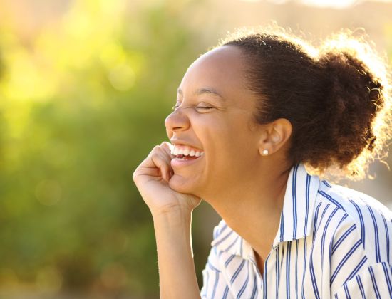 Young woman laughing outside in the sunshine.