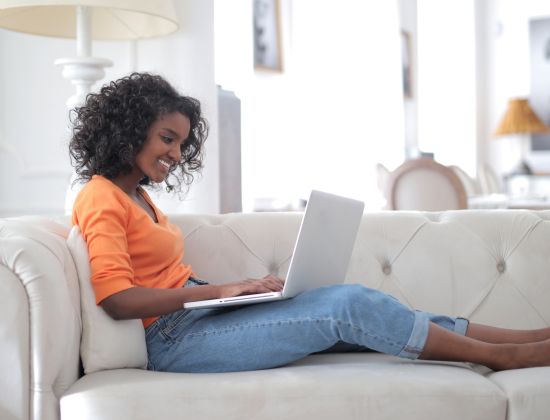 African American woman sitting on couch looking at laptop