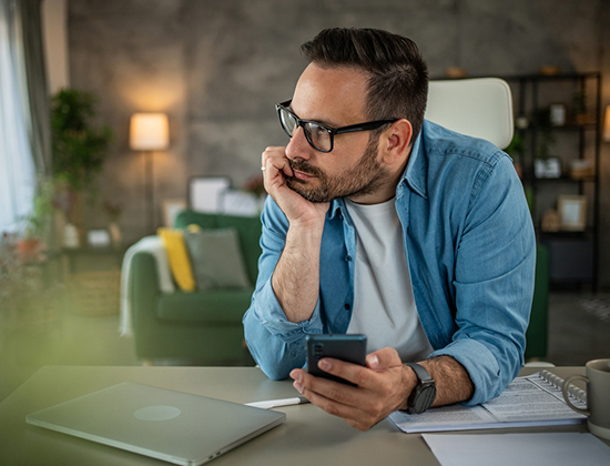 Man at desk gazing out window thinking about getting a secured loan