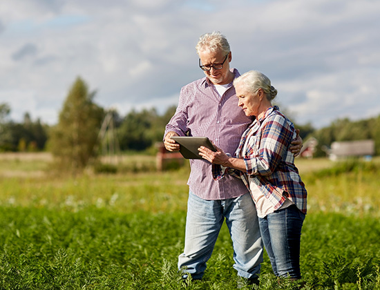 older couple in field with ipad