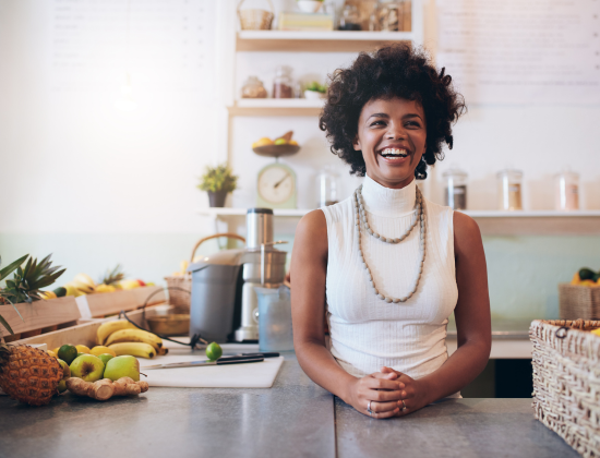 Laughing woman standing at counter in smoothie store.