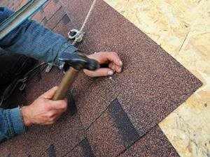 Man on a rooftop installing shingles in a home obtained thanks to a mortgage at MIDFLORIDA