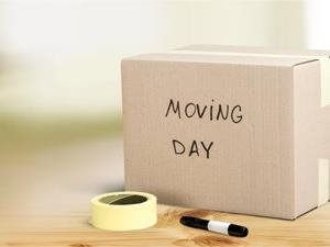 A medium box sitting on a wooden table with packing tape and a marker on moving day