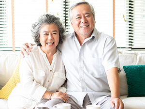 Two grandparents sitting on a couch smiling after obtaining a reverse mortgage