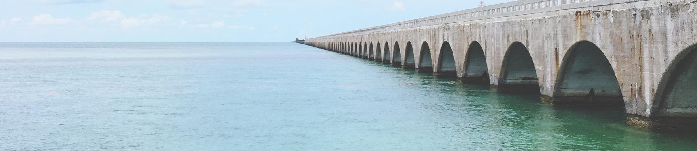 A long bridge next to a large body of water on a clear day